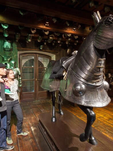 Eine Familie betrachtet eine große, gepanzerte Pferdestatue in einem Museum. Im Hintergrund sind weitere Rüstungen sichtbar. | © Graz Tourismus - Harry Schiffer
