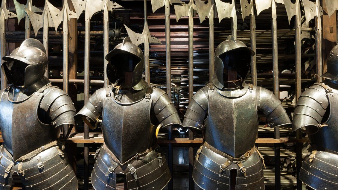 Eine Reihe von alten Rüstungen steht in einem Museen. Im Hintergrund sind zahlreiche Schwerter und Lanzen zu sehen. | © Graz Tourismus - Harry Schiffer