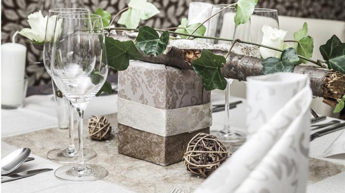 Ein elegant gedeckter Tisch mit Gläsern, Besteck und Dekoration aus Blumen und Zweigen. Die Farben sind neutral und harmonisch, ideal für eine festliche Atmosphäre. | © Landgasthof Erlsbacher