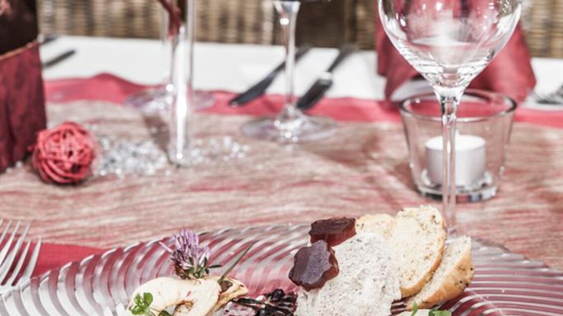 Ein elegantes Abendessen auf einem stilvollen Tisch. Auf dem Teller befinden sich kunstvoll angerichtete Speisen, umgeben von dekorativen Elementen. | © Landgasthof Erlsbacher