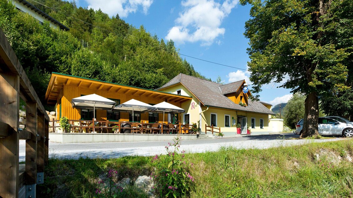 Ein gemütliches Restaurant mit einer großzügigen Terrasse und Sonnenschirmen. Umgeben von grünen Hügeln und blauem Himmel. | © TV Region Graz - Rene Vidalli