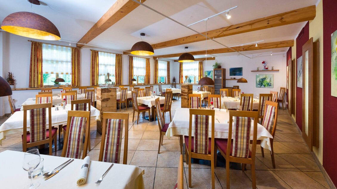 Ein heller, einladender Speisesaal mit Holzmöbeln und eleganten Tischdecken. Die großen Fenster sorgen für viel Tageslicht und eine gemütliche Atmosphäre. | © TV Region Graz - René Vidalli