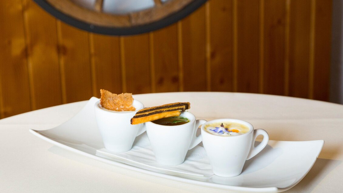 Drei kleine Tassen mit verschiedenen Desserts auf einem eleganten Teller. Im Hintergrund ist eine Holzwand zu sehen. | © TV Region Graz - René Vidalli