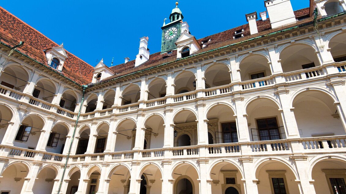 Ein historisches Gebäude mit einer schönen Fassade und vielen Bögen. Der Himmel ist klar und blau, was eine freundliche Atmosphäre schafft. | © Graz Tourismus - Harry Schiffer