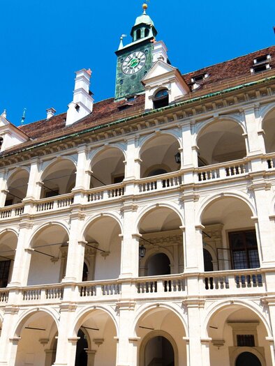 Ein historisches Gebäude mit einer schönen Fassade und vielen Bögen. Der Himmel ist klar und blau, was eine freundliche Atmosphäre schafft. | © Graz Tourismus - Harry Schiffer