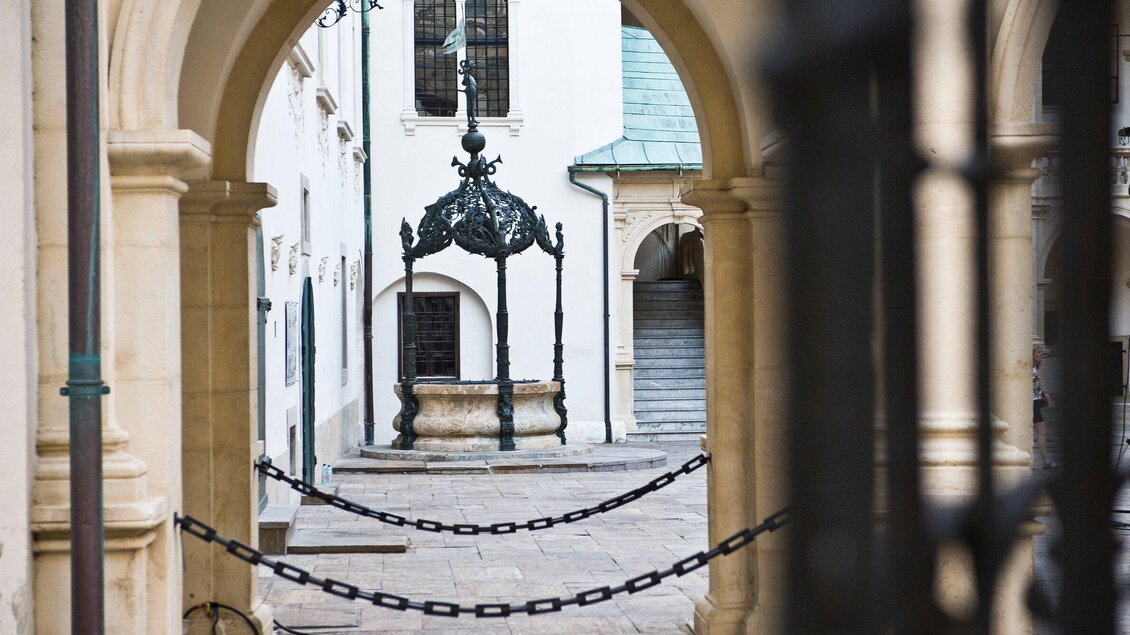 Ein schöner Innenhof mit einem historischen Brunnen in der Mitte. Der Zugang ist durch eine Kette gesperrt. | © Graz Tourismus - Toni Muhr