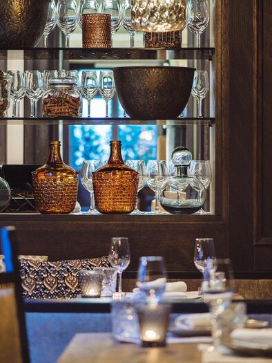 A cozy restaurant with elegant decor. In the background, stylish glasses and decorative vessels are visible. | © Landhauskeller