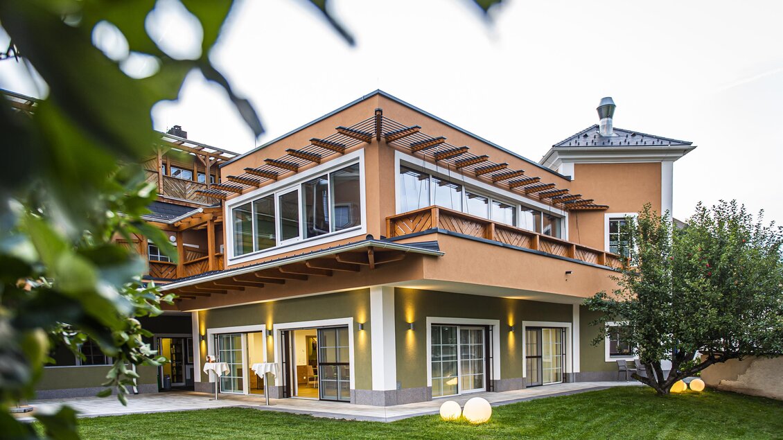 Ein modernes Haus mit großen Fenstern und einem gepflegten Garten. Die Architektur kombiniert Holz und Farbe für eine einladende Atmosphäre. | © Landhotel Timmerer
