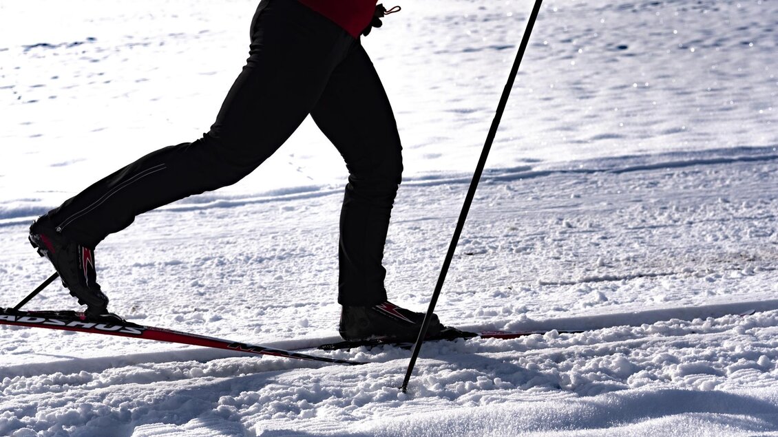 Eine Person beim Skilanglauf auf einer verschneiten Fläche. Der Skifahrer trägt schwarze Hose und einen roten Oberteil. | © Erlebnisregion Murtal