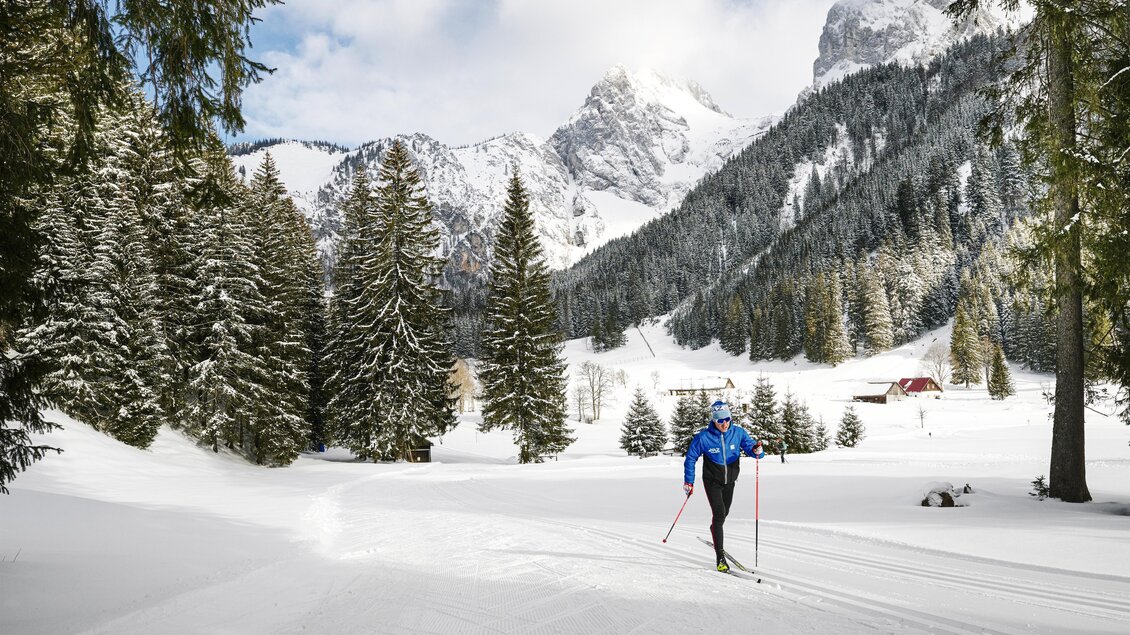 Ein Skilangläufer bewegt sich durch eine schneebedeckte Landschaft. Im Hintergrund sind hohe Berge und dichte Wälder zu sehen. | © TVB Erzberg-Leoben