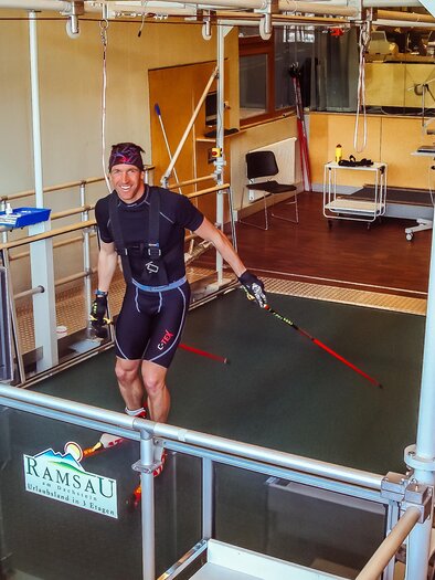 A man is training on a special treadmill in a modern sports lab. He is wearing a tracksuit and modern performance analysis equipment. | © Leistungszentrum Ramsau