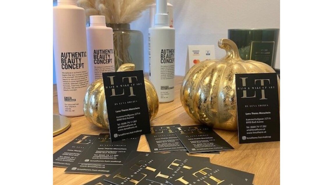 Eine stilvolle Präsentation von Haarpflegeprodukten auf einem Holztisch. Goldene Kürbisse und Visitenkarten verleihen dem Arrangement eine elegante Note. | © TVB Ausseerland- Salzkammergut_Heike Temmel