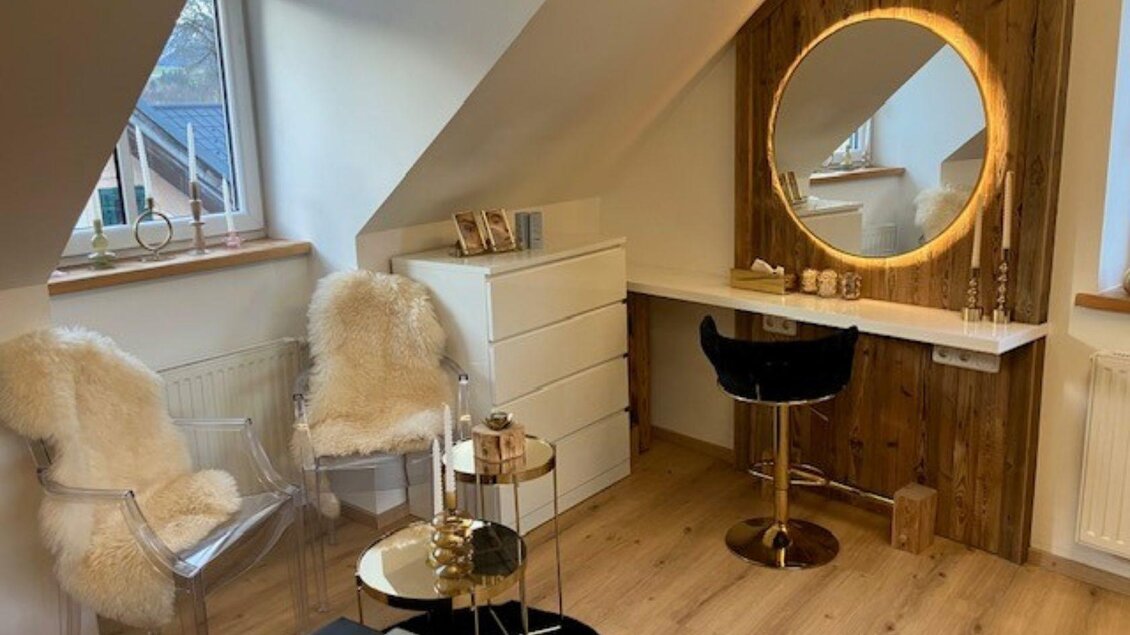 Ein stilvolles Zimmer mit einem schönen Schminktisch und runden Spiegel. Es gibt helle Stühle und eine warme Holzverkleidung, die einladend wirkt. | © TVB Ausseerland- Salzkammergut_Heike Temmel