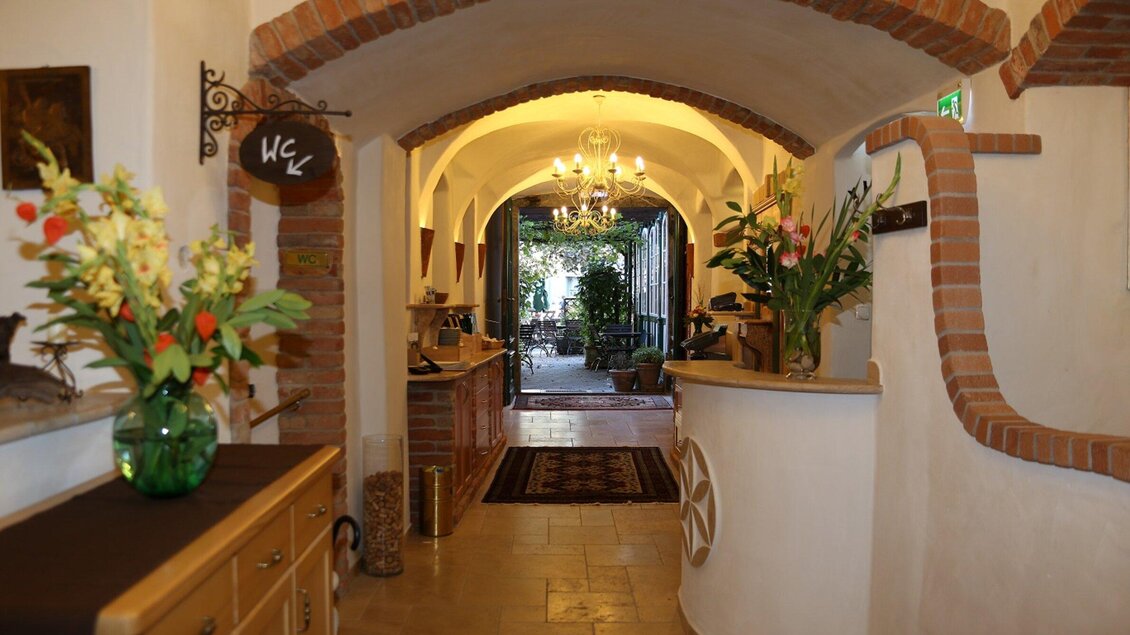 Ein einladender Empfangsbereich mit einem hellen Flur und schönen Pflanzen. Im Hintergrund sieht man eine gemütliche Sitzecke und historische Details. | © Lendplatzl