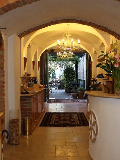 Ein einladender Empfangsbereich mit einem hellen Flur und schönen Pflanzen. Im Hintergrund sieht man eine gemütliche Sitzecke und historische Details. | © Lendplatzl