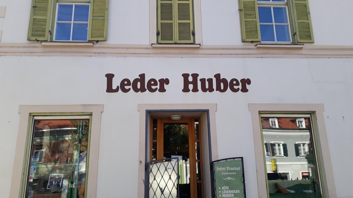 Ein Geschäft mit dem Namen „Leder Huber“. Die Fassade ist hell mit grünen Fensterläden. | © Schilcherland Steiermark