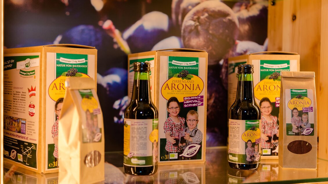 Eine Ausstellung mit verschiedenen Aronia-Produkten, darunter Flaschen und Verpackungen. Die Farben sind lebhaft und die Produkte sind ansprechend präsentiert. | © Erlebnisregion Murtal