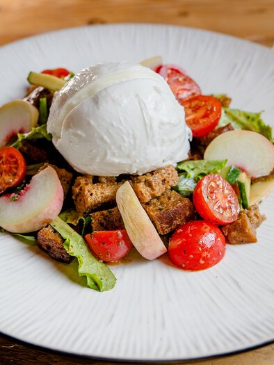 Ein frisch zubereitetes Gericht mit Salat, Kirschtomaten und geröstetem Brot. Obenauf liegt ein pochiertes Ei. | © Region Graz - Mias Photoart