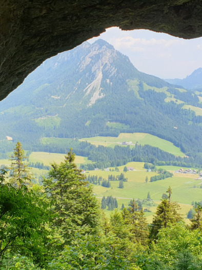 A view from a cave onto a green landscape with mountains in the background. The nature is lush and invites exploration. | © Daniela Casari