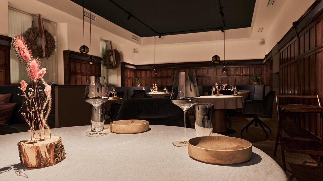 Ein stilvolles Restaurant mit eleganten Tischen und schönen Dekorationen. Die warme Beleuchtung schafft eine einladende Atmosphäre.