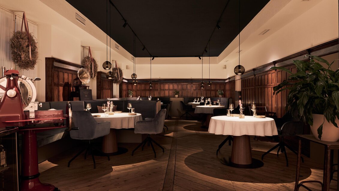 Ein elegantes Restaurant mit stilvollen Tischen und bequemen Stühlen. Die Atmosphäre ist warm und einladend, mit sanfter Beleuchtung und dekorativen Elementen.