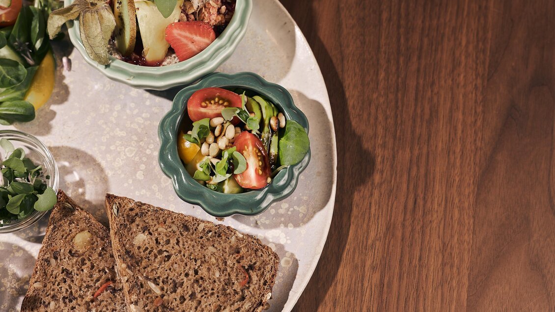 Ein Teller mit frischem Salat, Gemüse und einer Scheibe Brot. Die Farben sind lebendig und einladend.