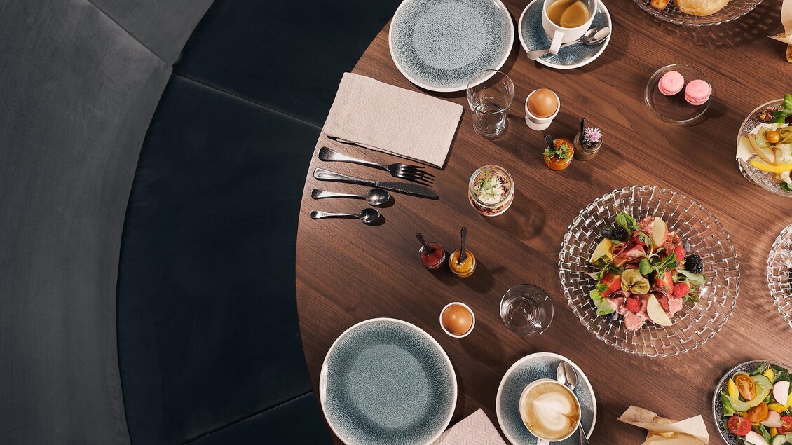 Ein schön gedeckter Tisch mit Tellern, Besteck und einer Auswahl an Speisen. Die Atmosphäre ist einladend und gemütlich.