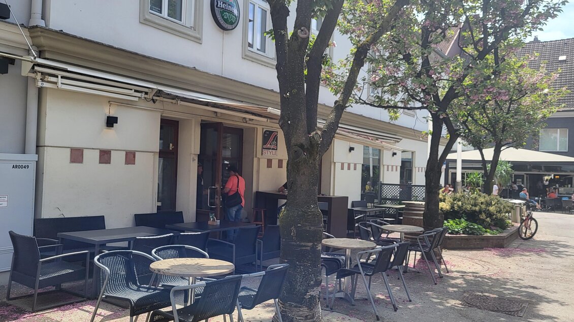 Ein gemütliches Café mit Tischen im Freien und einem großen Baum. Die Umgebung ist einladend und hell, ideal für eine entspannte Auszeit. | © TV Hochsteiermark