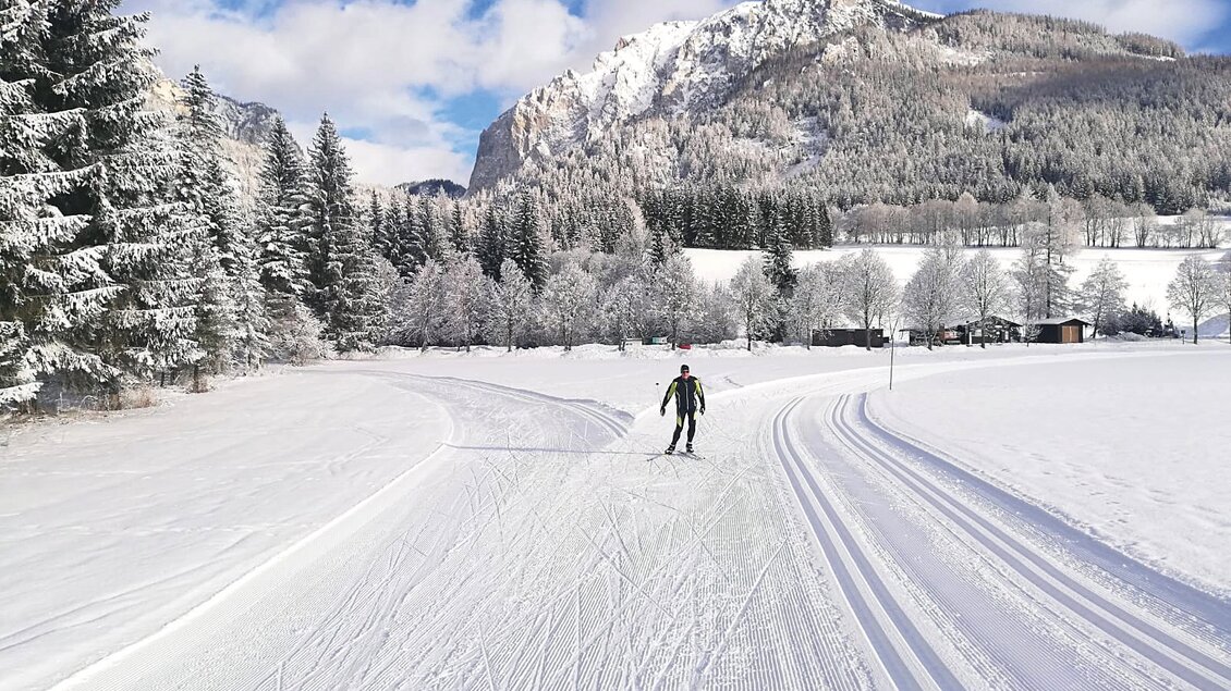 Eine schneebedeckte Landschaft mit einem beeindruckenden Berg im Hintergrund. Einige Menschen gehen auf einer verschneiten Fläche. | © Otto Rinnerhofer