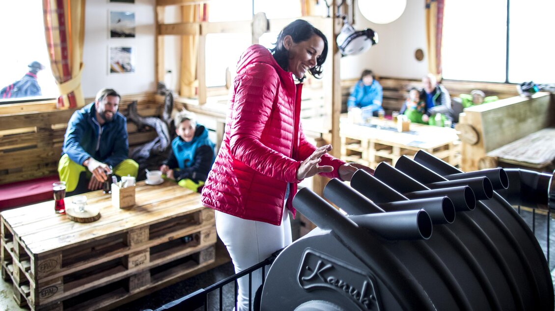 Eine Person in einem roten Kleidungsstück spielt im Innenbereich mit einem Musikinstrument. Im Hintergrund entspannen sich weitere Personen in einer gemütlichen Umgebung. | © TVB Ausseerland-Salzkammergut / Tom Lamm