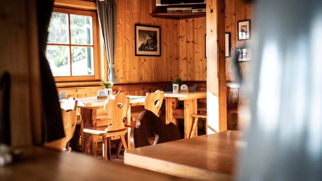 Ein gemütliches Restaurant mit holzgetäfelten Wänden und Tischen. Die Stühle haben Herzformen und es gibt natürliches Licht, das durch die Fenster strahlt. | © Chris Gütl