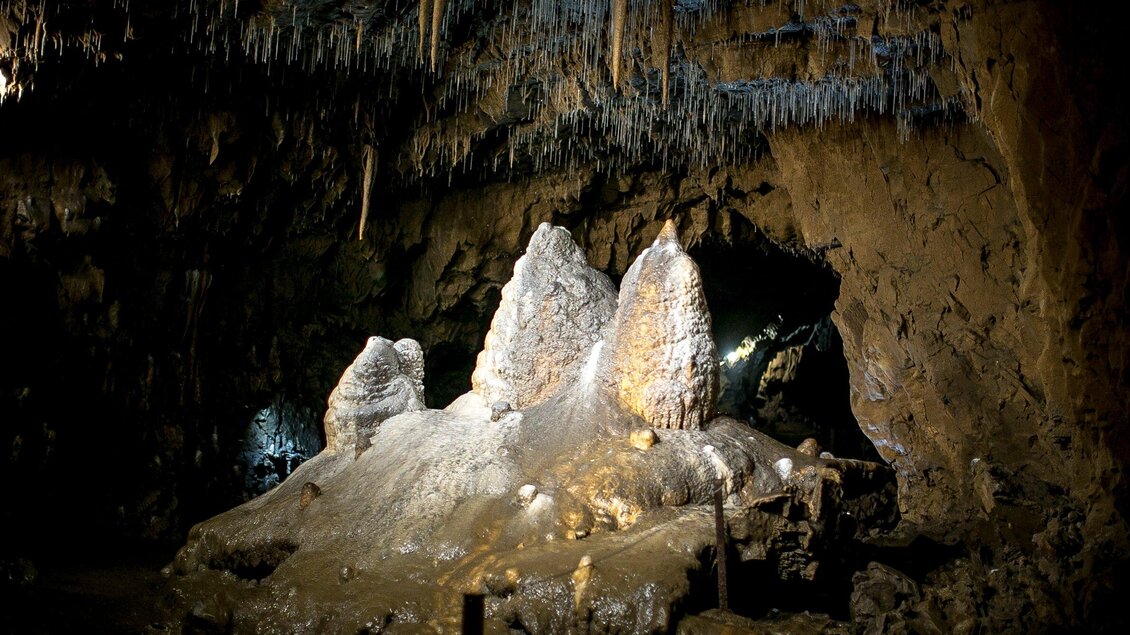 Ein faszinierender Höhlenraum mit ausgeprägten Stalaktiten und Stalagmiten. Die Umgebung ist düster, mit sanfter Beleuchtung, die die Formationen hervorhebt. | © Region Graz - Tom Lamm