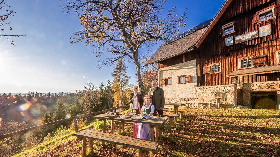 Eine Gruppe von Menschen steht vor einem gemütlichen Bauernhaus in einer malerischen Landschaft. Der Himmel ist klar und die Umgebung wirkt einladend und herbstlich. | © Stift Rein - Pater Martin