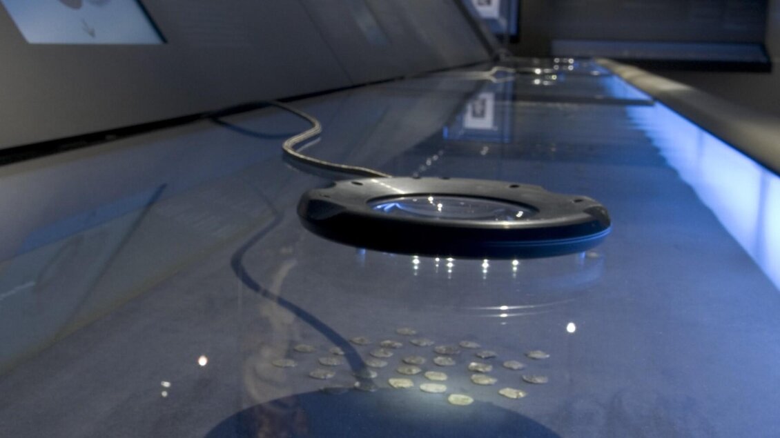 Nahaufnahme einer Vitrine mit historischen Münzen und integrierter Lupe im Schloss Eggenberg | © UMJ-Nicolas Lackner