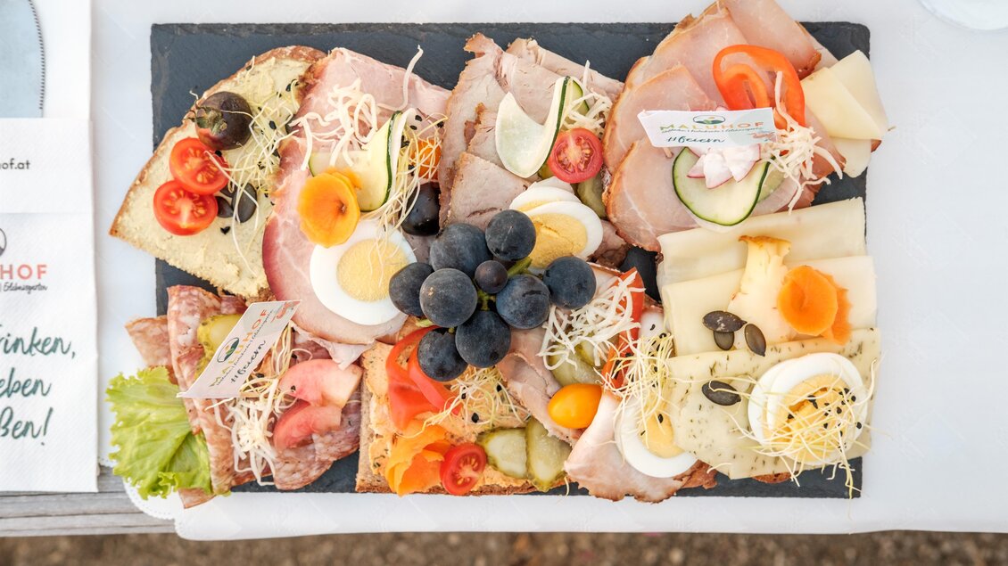 Ein köstliches Vesperbrett mit verschiedenen Aufschnittsorten, Käse und frischem Gemüse. Darauf befinden sich auch Trauben und Eier. | © MALU