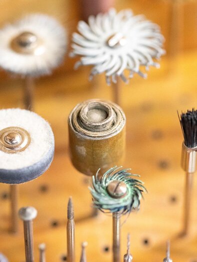 A variety of tools and brushes for craft work, arranged on a wooden board. The tools are made in different shapes and materials. | © Schmuck Design, Marion Buchsteiner