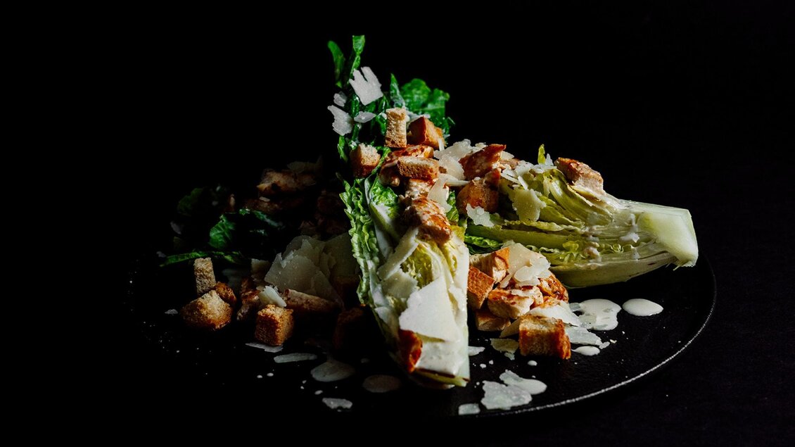 Caesar Salad mit Romanasalat, Croutons, Parmesan und Dressing. | © MEAT.art - Simona Donko