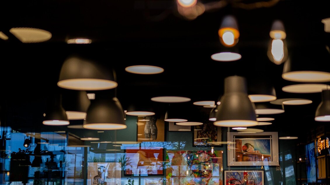 Blick auf Wandbilder, Spiegelungen und Deckenleuchten im modern gestalteten Innenraum. | © MEAT.art - Simona Donko