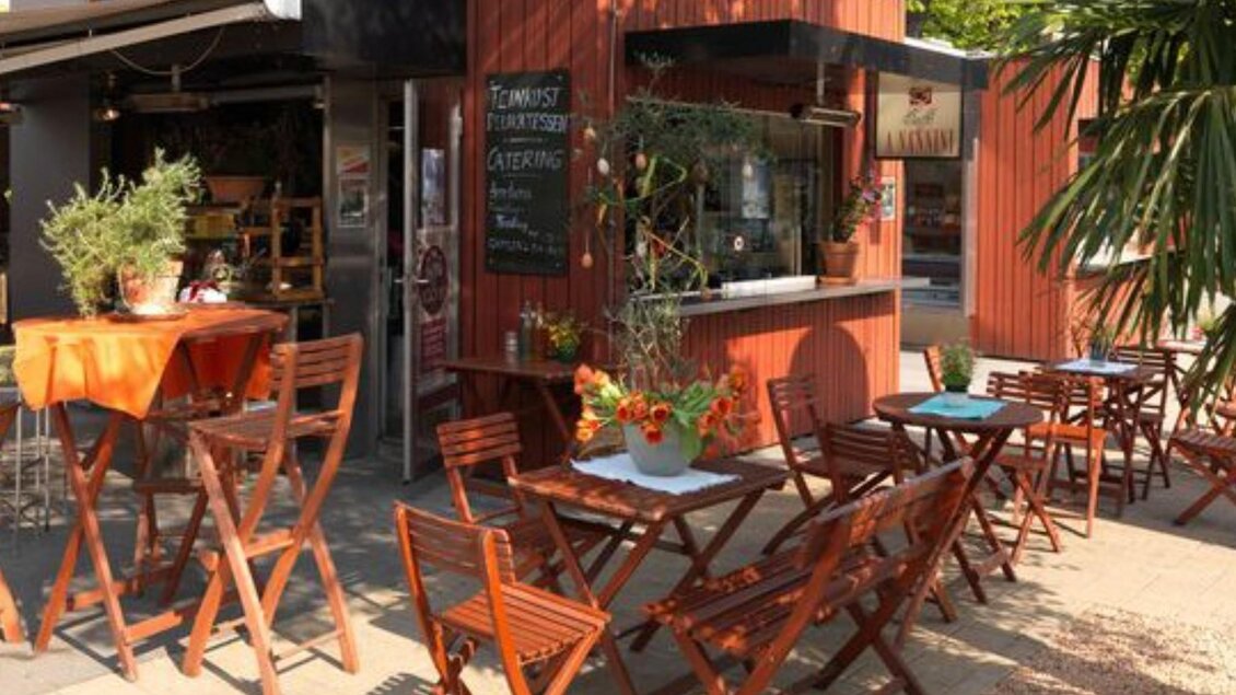 Außenbereich mit Holztischen und Stühlen, Blumendekoration und Sonnenschein | © Macello