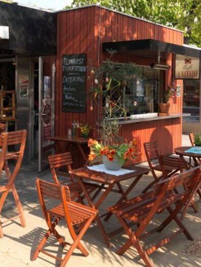 Outdoor area with wooden tables and chairs, flower decoration, and sunshine | © Macello