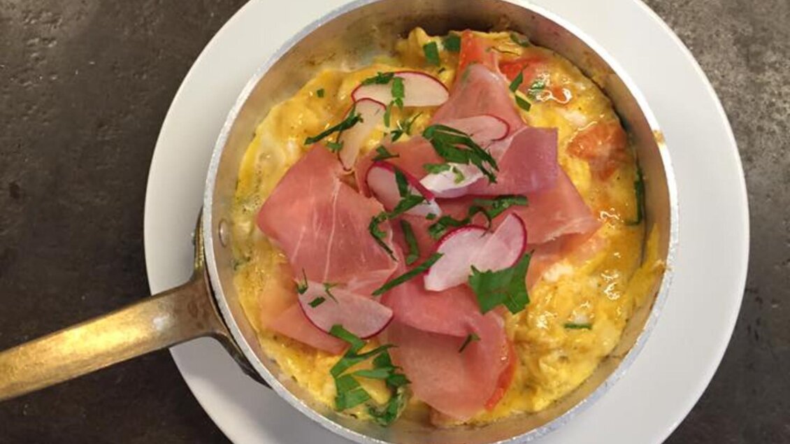 Kleine Pfanne mit Eierspeise, belegt mit Schinken, Radieschenscheiben und Kräutern auf weißem Teller | © Macello