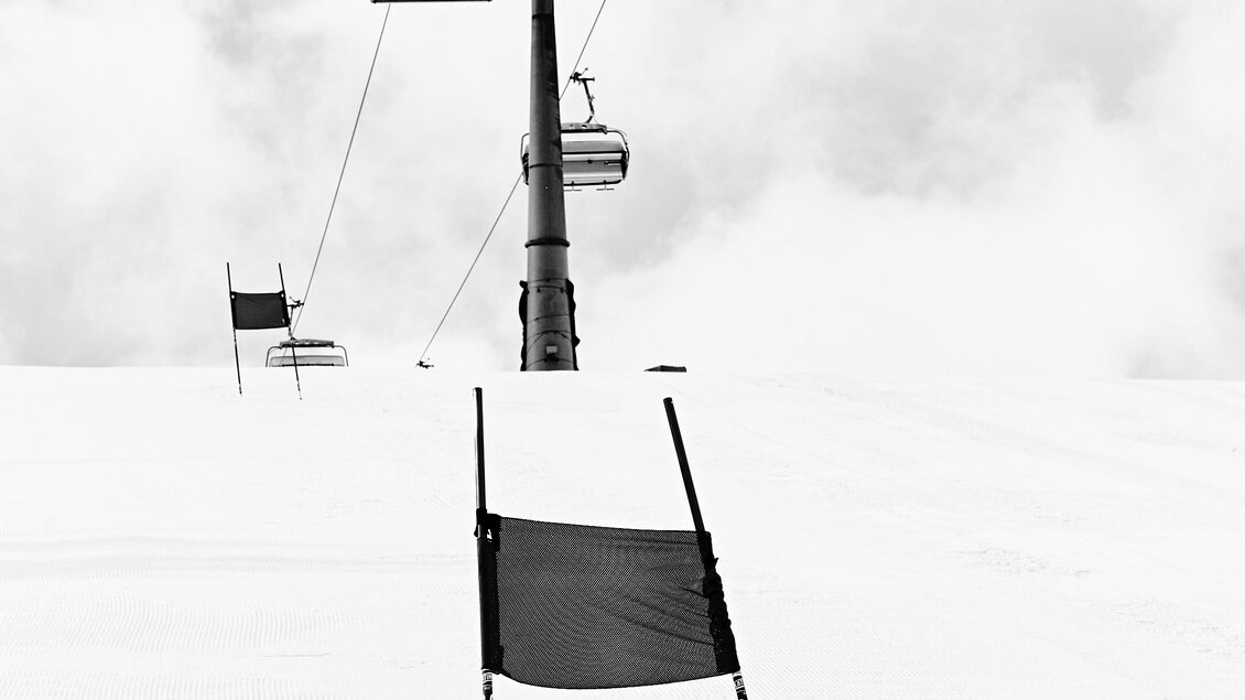 Ein leeres Skigebiet mit einem Sessellift und Pistenmarkierungen. Die Landschaft ist schneeweiß und winterlich. | © Armin Walcher