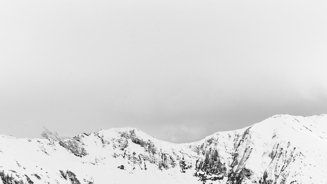 Eine schneebedeckte Berglandschaft unter einem klaren, grauen Himmel. Die Berge sind majestätisch und strahlen Ruhe aus. | © Armin Walcher