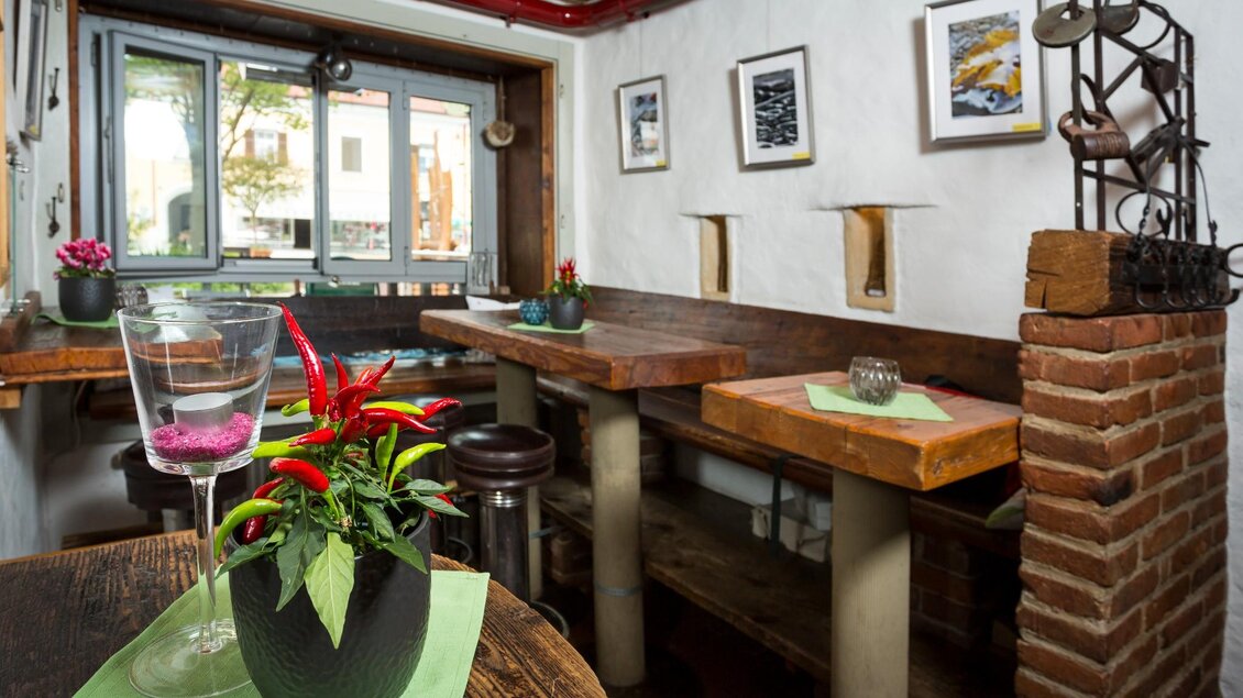 Innenraum des Restaurants Tavernetta Dallo Spazzacamino mit Holztischen, Dekoration und Fensterblick in Frohnleiten. | © TV Region Graz - René Vidalli
