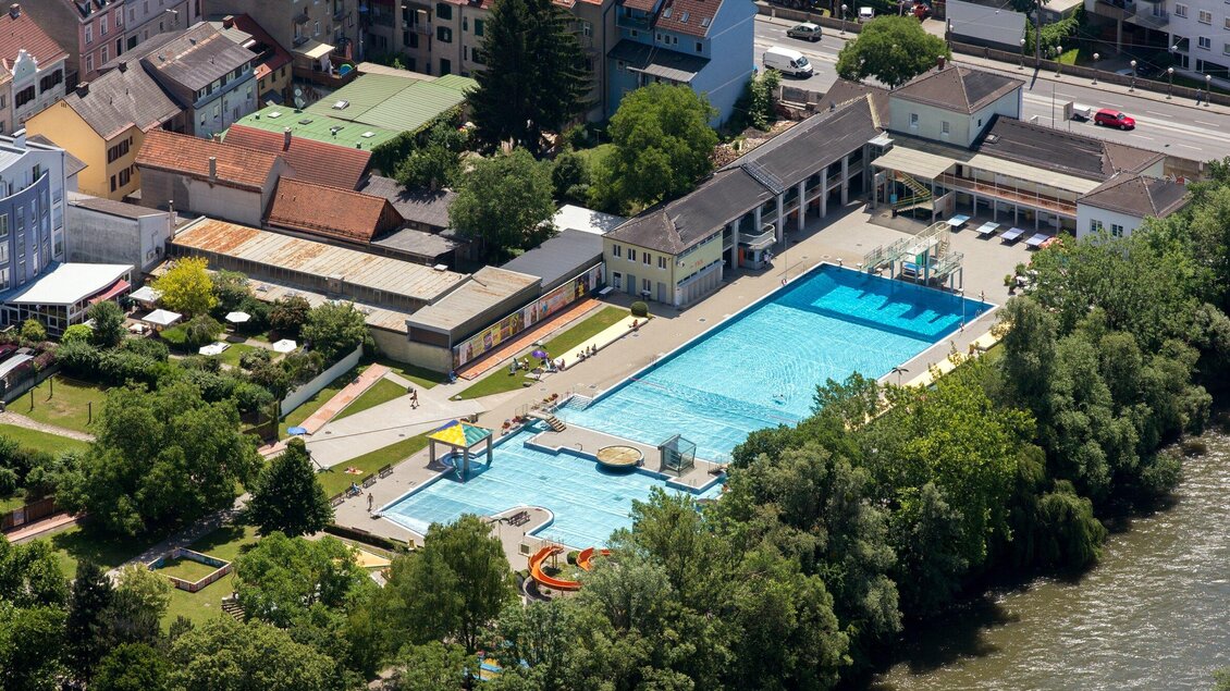 Das Margaretenbad mit herrlich  blauem Wasser und umgeben von Grünflächen. Im Hintergrund sind Häuser und Bäume der Stadt Graz zu sehen. | © Graz Tourismus - Harry Schiffer