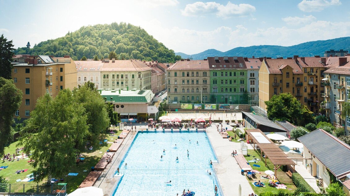 Das Margaretenbad im Stadtzentrum von Graz umgeben von Wohngebäuden. Menschen genießen die Sonne und das Wasser. | © Holding Graz - Joel Kernasenko