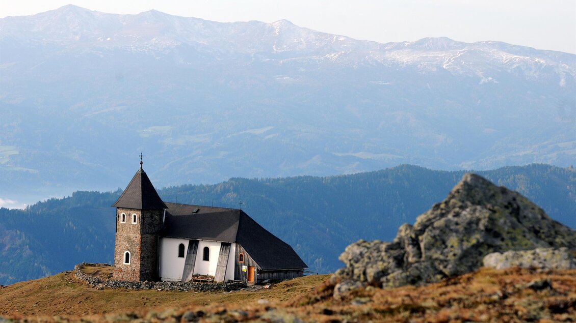 Eine idyllische Kirche auf einem Hügel mit beeindruckendem Bergpanorama im Hintergrund. Die Landschaft ist ruhig und zieht den Blick auf die natürliche Schönheit der Umgebung. | © Erlebnisregion Murtal