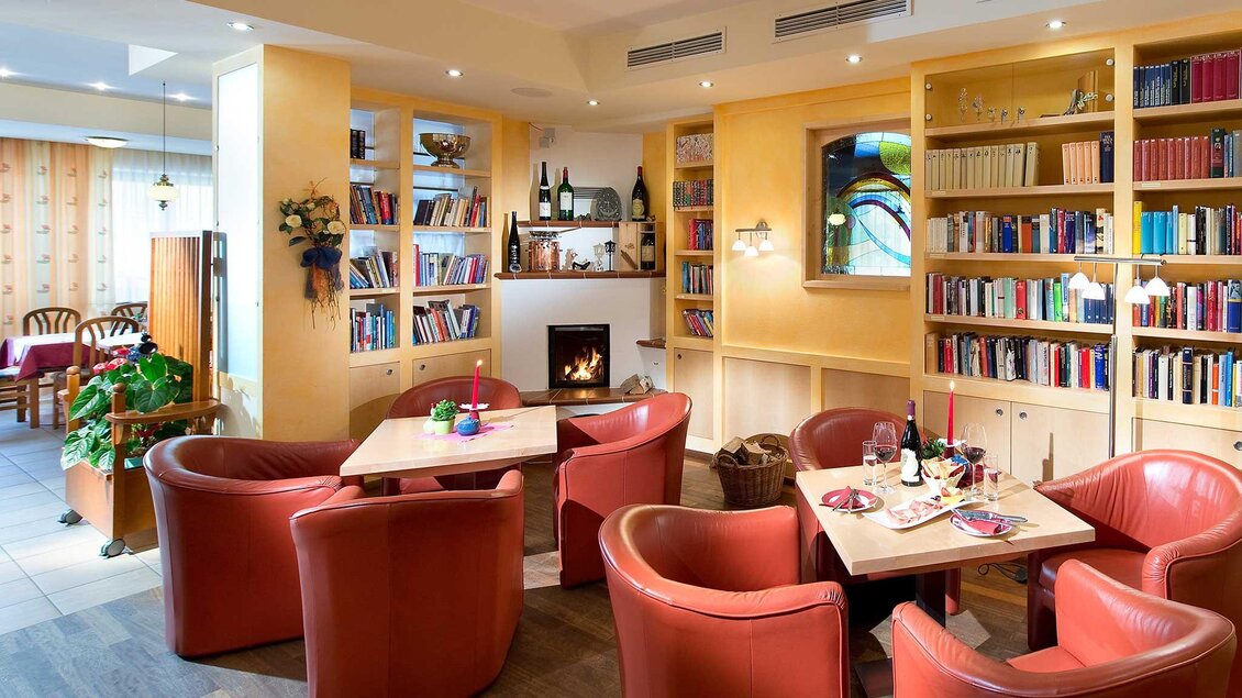 Ein gemütliches Café mit roten Sesseln und einem Bücherregal auf der rechten Seite. Im Hintergrund gibt es einen Kamin, der eine einladende Atmosphäre schafft. | © Tourismusverband Murau