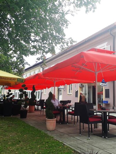 A restaurant with red umbrellas outside. The guests are sitting at tables and enjoying the atmosphere. | © Marktcafé Wildbacher