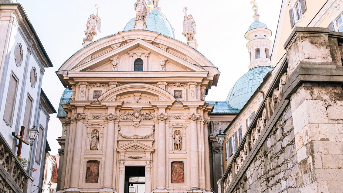 Eine beeindruckende Kirche mit einer kunstvollen Fassade und einer Kuppel. Die Architektur zeigt barocke Details und ist von historischen Gebäuden umgeben. | © Graz Tourismus